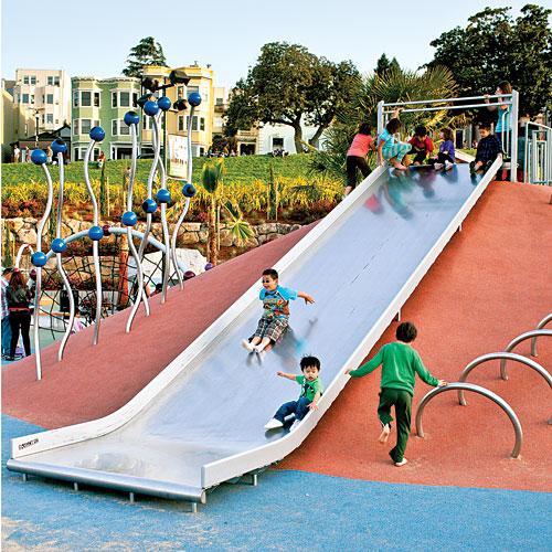 Kids go down a giant slide at a whimsical-looking playground.